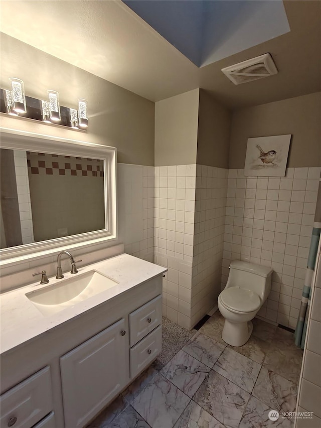 bathroom featuring vanity, tile walls, and toilet