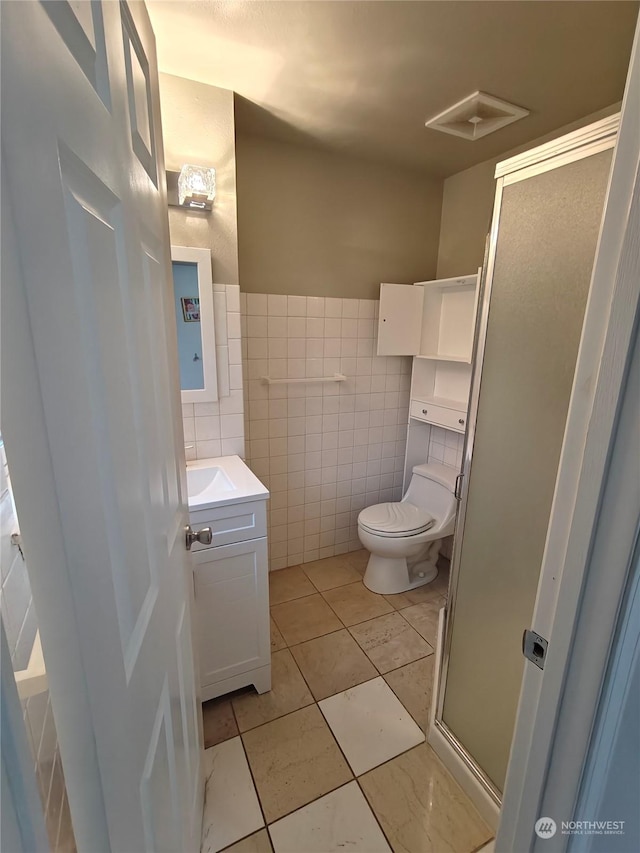 bathroom featuring tile patterned floors, vanity, tile walls, and toilet