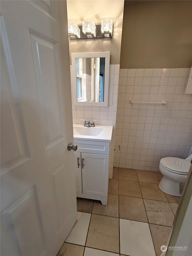 bathroom featuring tile patterned flooring, vanity, tile walls, and toilet