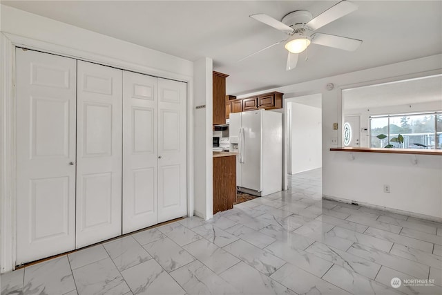 1675 S 57th St, Tacoma, WA 98408 - kitchen featuring white fridge with ice dispenser, light marble finish floors, brown cabinetry, and ceiling fan