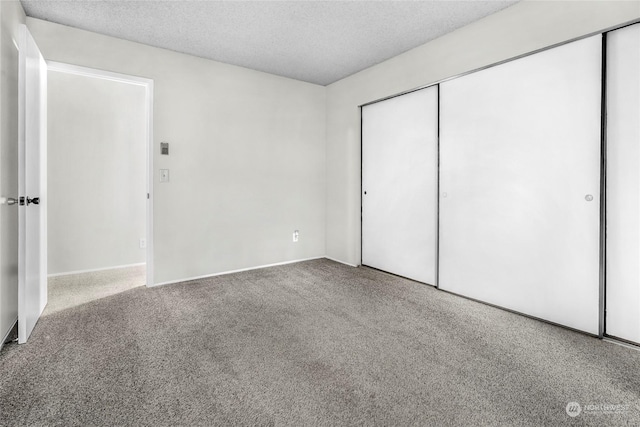 unfurnished bedroom featuring a textured ceiling, carpet floors, and a closet