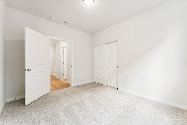 unfurnished bedroom featuring light colored carpet and a closet