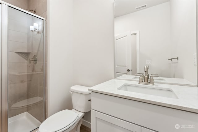 bathroom featuring vanity, toilet, and a shower with shower door