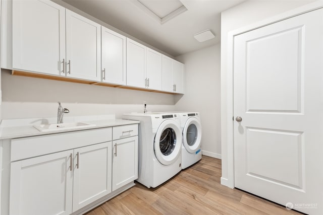 washroom with cabinets, sink, washing machine and clothes dryer, and light hardwood / wood-style floors