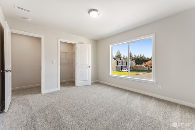 unfurnished bedroom featuring a spacious closet, light colored carpet, and a closet