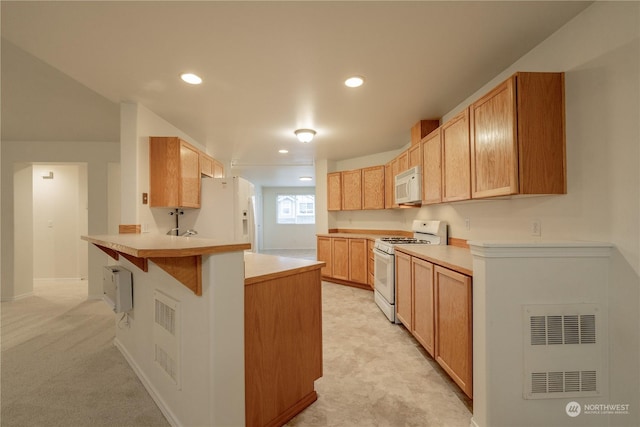 kitchen featuring light brown cabinets, a kitchen breakfast bar, kitchen peninsula, light colored carpet, and white appliances