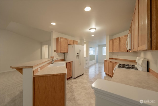 kitchen with kitchen peninsula, light brown cabinetry, white appliances, and sink