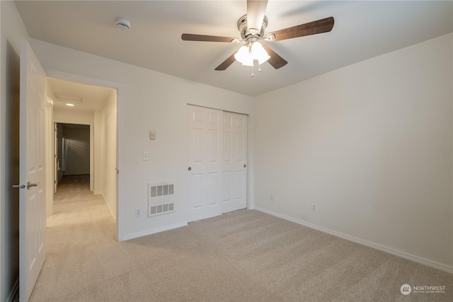 unfurnished bedroom featuring ceiling fan, a closet, and light colored carpet