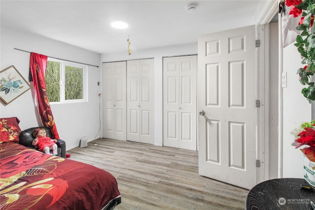 bedroom featuring multiple closets and light hardwood / wood-style flooring