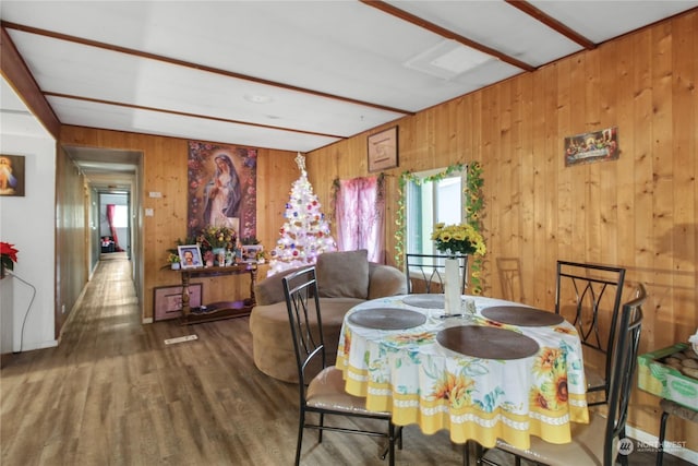 dining area featuring wood walls, beamed ceiling, and dark hardwood / wood-style floors