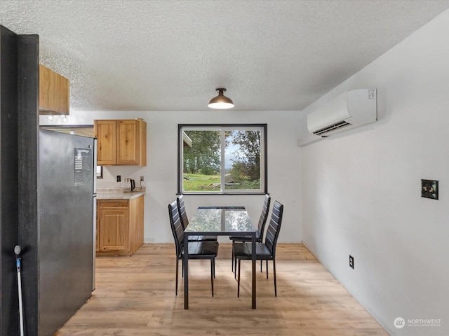 dining area with a wall unit AC, light hardwood / wood-style flooring, and a textured ceiling