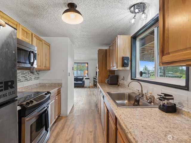 kitchen with a wealth of natural light, sink, light hardwood / wood-style flooring, and appliances with stainless steel finishes