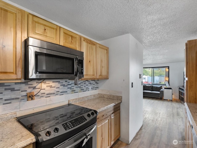 kitchen featuring decorative backsplash, a textured ceiling, stainless steel appliances, light brown cabinets, and light hardwood / wood-style floors