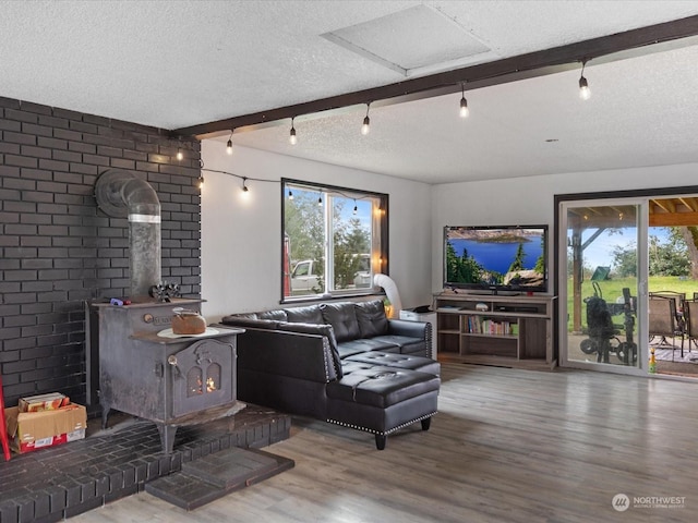 living room with beam ceiling, a textured ceiling, a wood stove, and a wealth of natural light