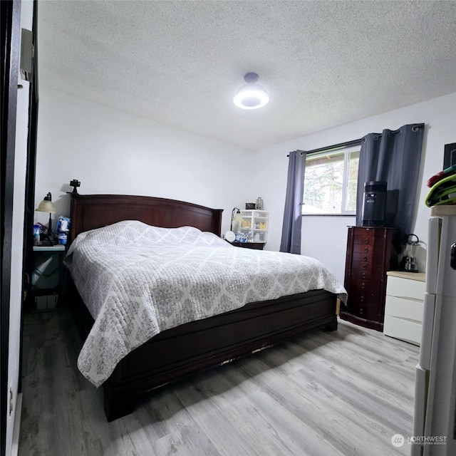 bedroom with light hardwood / wood-style flooring and a textured ceiling