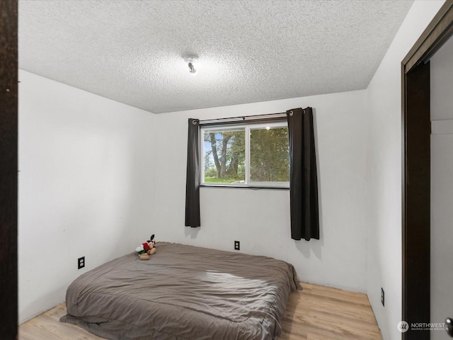 bedroom featuring light hardwood / wood-style floors and a textured ceiling