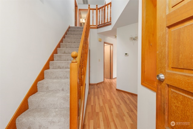 stairway with wood-type flooring and a towering ceiling