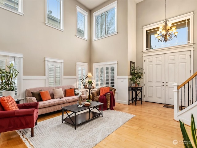 living room featuring hardwood / wood-style floors, a towering ceiling, an inviting chandelier, and plenty of natural light