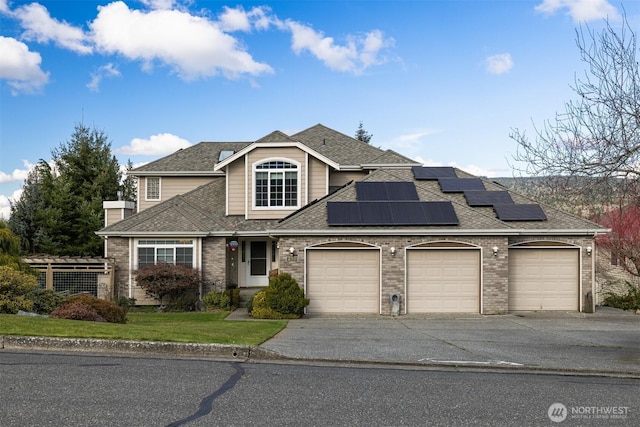 traditional home with brick siding, aphalt driveway, roof with shingles, roof mounted solar panels, and a garage