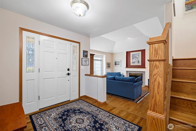 entryway featuring stairway, wood finished floors, and a fireplace