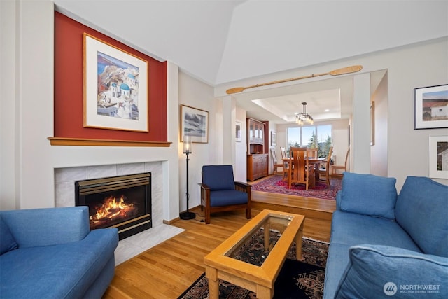 living room featuring a raised ceiling, light wood-style floors, lofted ceiling, and a fireplace