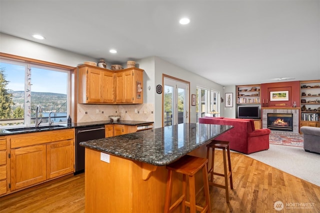 kitchen with dishwasher, a kitchen bar, light wood-style floors, and a sink