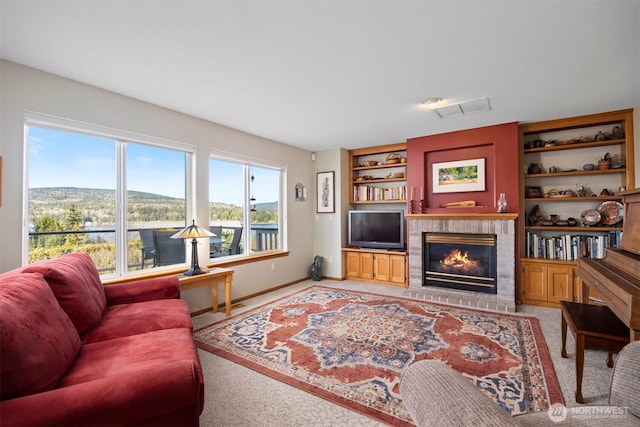 living area featuring visible vents, built in shelves, baseboards, light carpet, and a fireplace