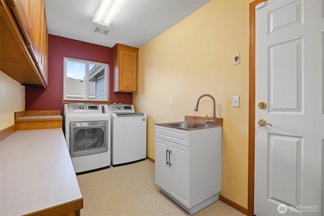 washroom with visible vents, a sink, baseboards, cabinet space, and separate washer and dryer