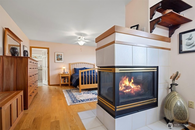 bedroom featuring a multi sided fireplace and light wood-style flooring