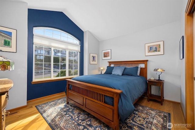 bedroom with baseboards, wood finished floors, and vaulted ceiling