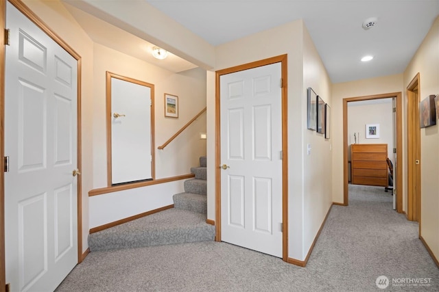 hallway featuring carpet flooring, stairway, and baseboards