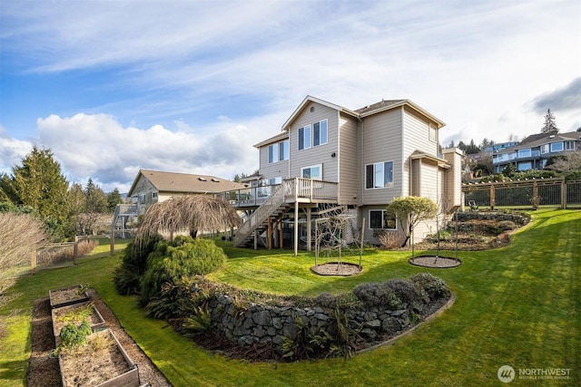 back of property with stairway, fence, a vegetable garden, a yard, and a deck