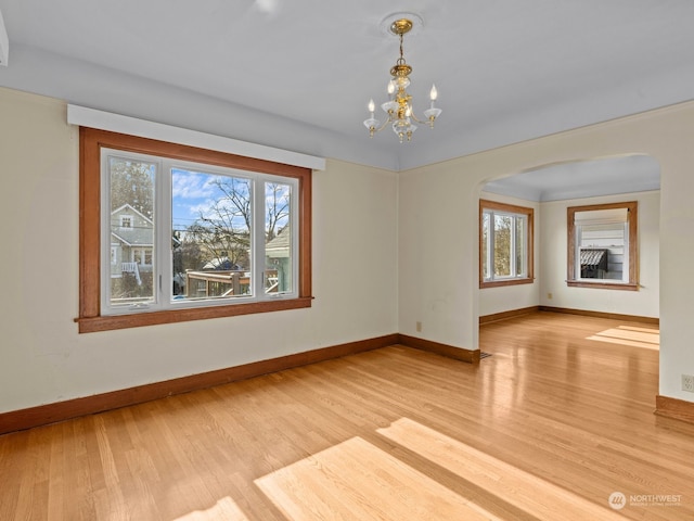 empty room with hardwood / wood-style flooring and a chandelier