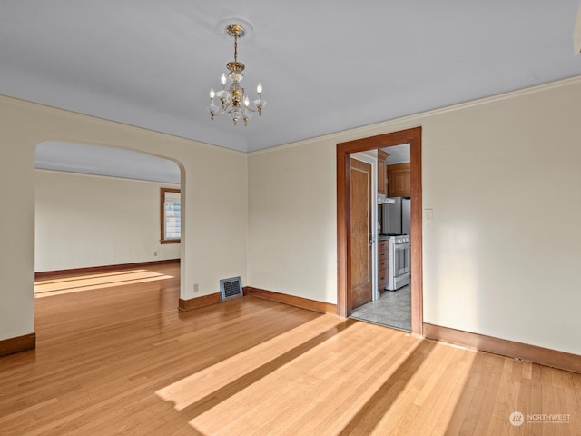 empty room featuring crown molding, a chandelier, and light hardwood / wood-style floors