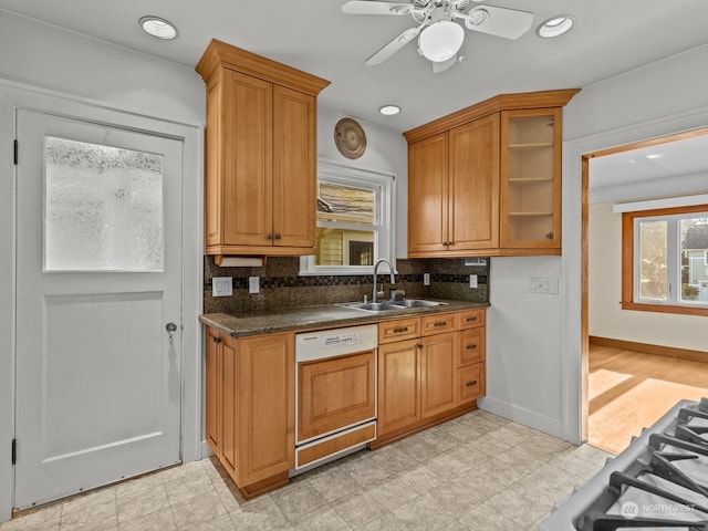 kitchen with sink, tasteful backsplash, dark stone countertops, ceiling fan, and paneled dishwasher