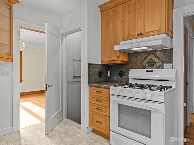 kitchen with stone counters, white range with gas cooktop, a chandelier, and backsplash