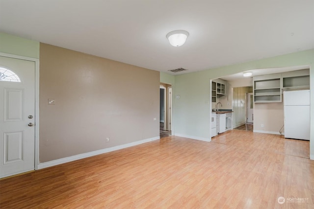 unfurnished living room with light wood-type flooring and sink