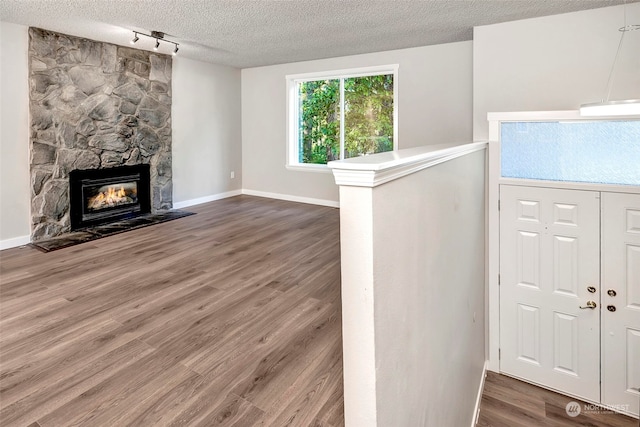 entryway with a fireplace, wood-type flooring, rail lighting, and a textured ceiling