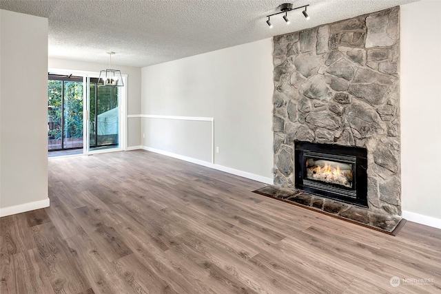 unfurnished living room with hardwood / wood-style flooring, a fireplace, a textured ceiling, and rail lighting