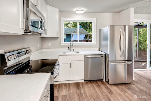 kitchen featuring white cabinetry, sink, stainless steel appliances, a healthy amount of sunlight, and light hardwood / wood-style flooring