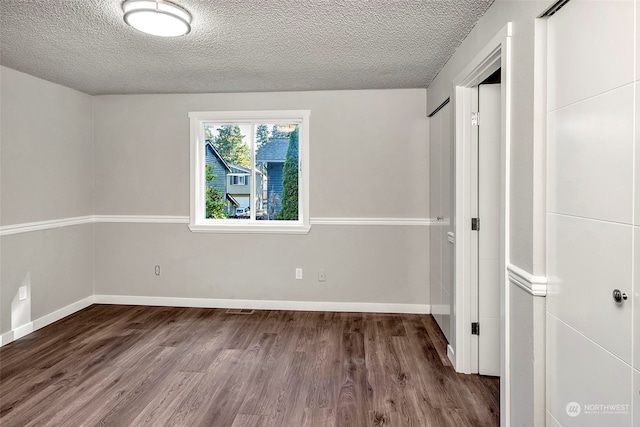 spare room with dark wood-type flooring and a textured ceiling