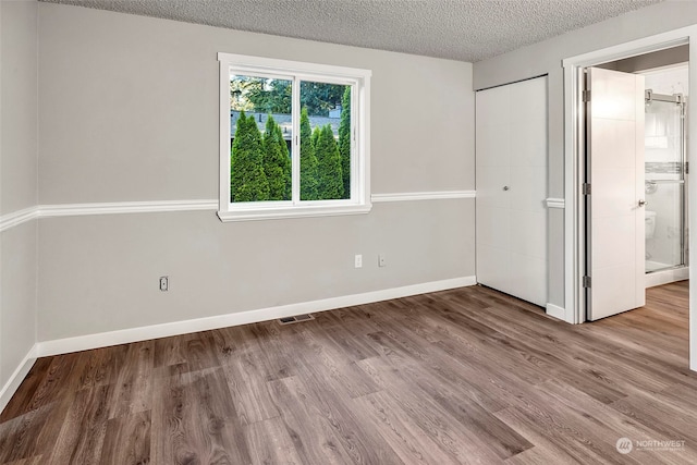 unfurnished bedroom featuring hardwood / wood-style floors and a textured ceiling