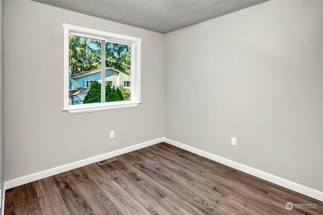 unfurnished room featuring hardwood / wood-style flooring and a textured ceiling