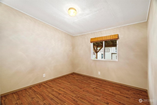 empty room featuring hardwood / wood-style floors, ornamental molding, and a textured ceiling