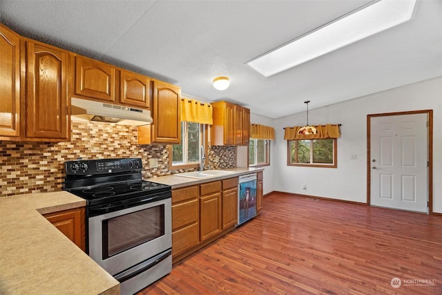 kitchen with stainless steel range with electric stovetop, dishwasher, pendant lighting, lofted ceiling with skylight, and sink