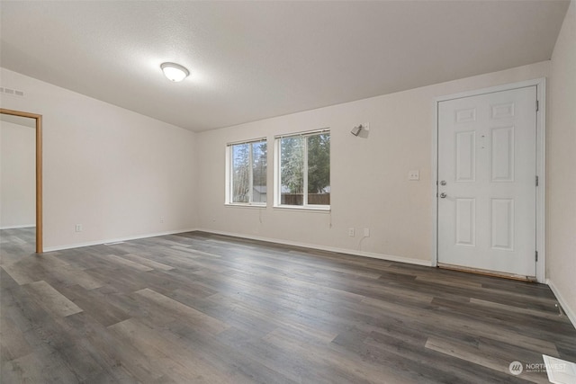 spare room featuring dark hardwood / wood-style floors and a textured ceiling