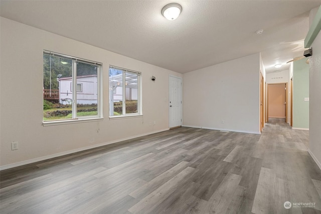 spare room with a textured ceiling and light wood-type flooring