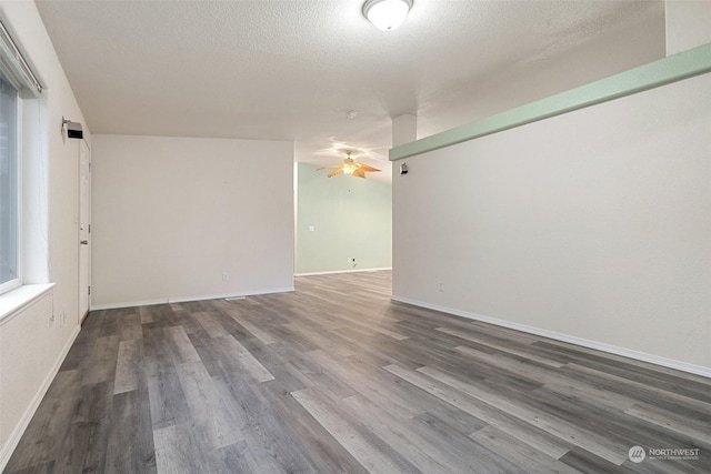 spare room with dark wood-type flooring, a textured ceiling, and ceiling fan