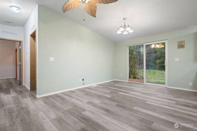 empty room with ceiling fan with notable chandelier and light wood-type flooring