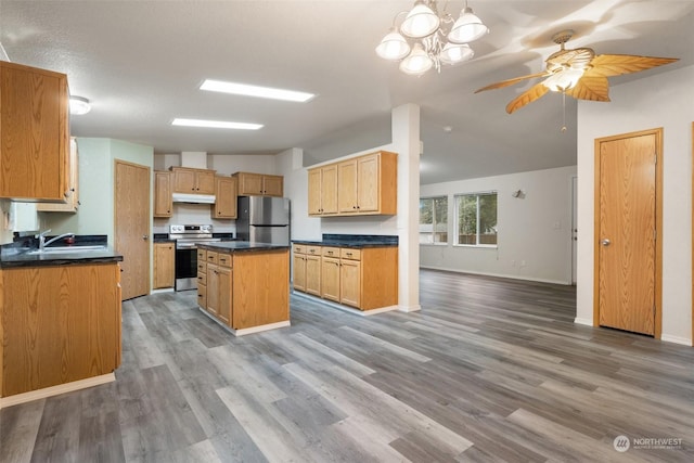 kitchen with appliances with stainless steel finishes, sink, a kitchen island, and light wood-type flooring